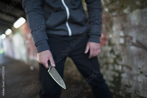 Young man holding knife weapon in tunnel photo