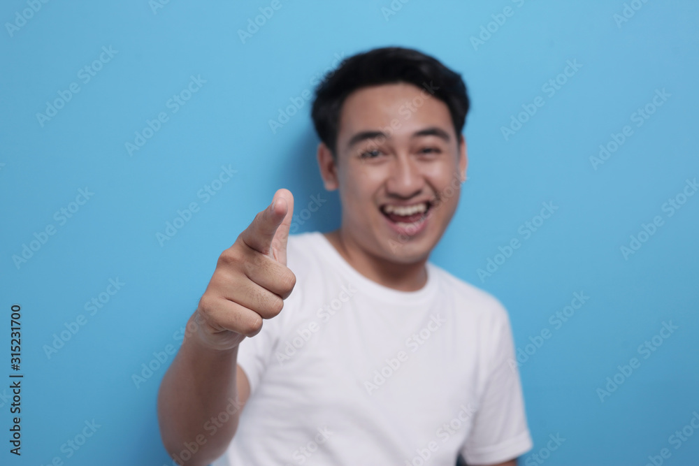 Asian young man pointing forward, looking at camera Asian young man pointing forward, looking at camera