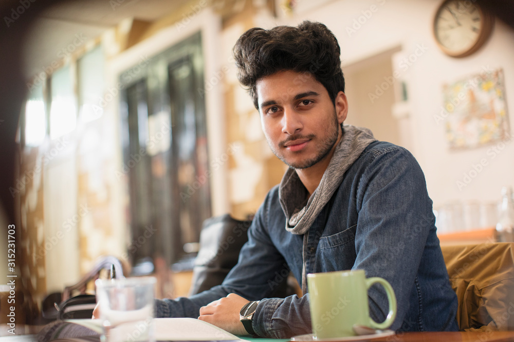 Portrait confident young male college student studying in cafe Portrait confident young male college student studying in cafe