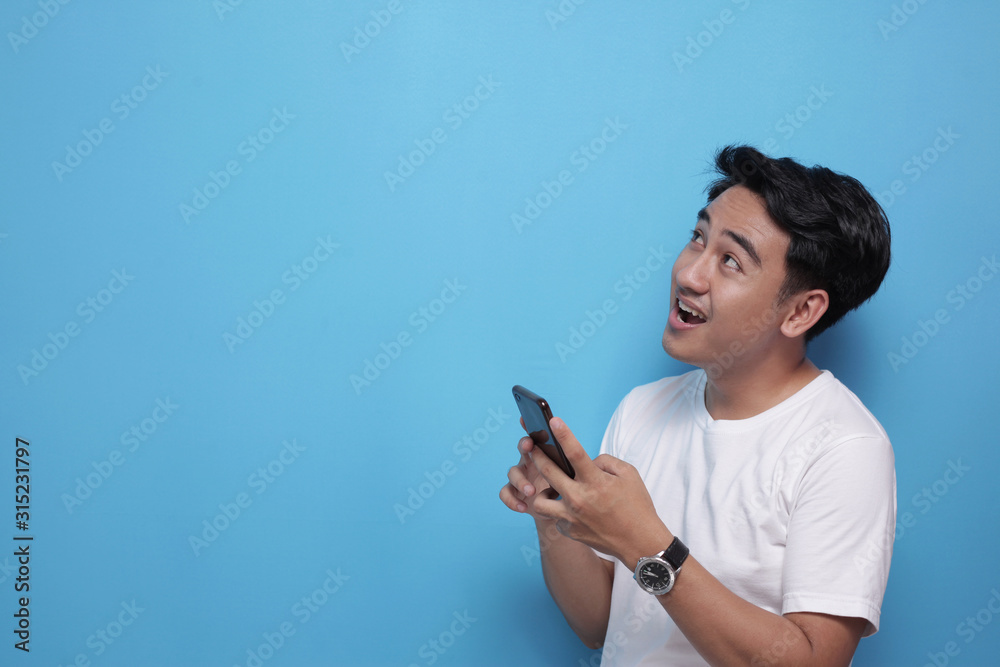 Young Man Surprised to See Something Above when using Phone Young Man Surprised to See Something Above when using Phone