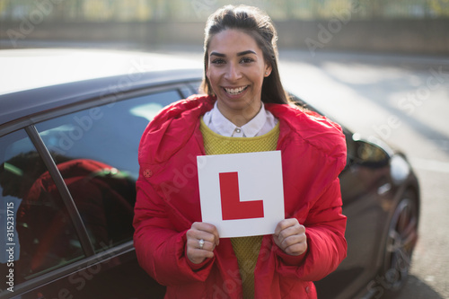 Portrait confident, happy young woman holding learners permit by car photo