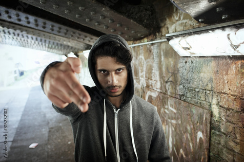 Portrait tough young man gesturing finger gun in urban tunnel photo