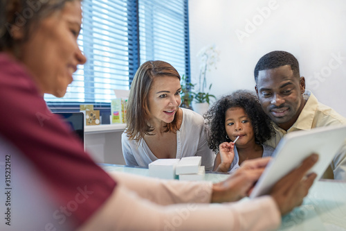 Doctor with digital tablet talking to family in doctors office