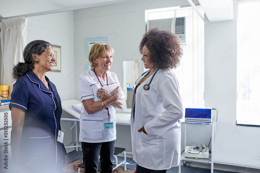 Female doctor and nurses talking in clinic examination room Female doctor and nurses talking in clinic examination room