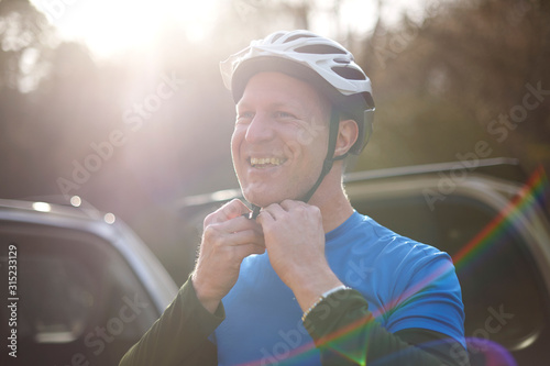 Portrait smiling man fastening bike helmet photo