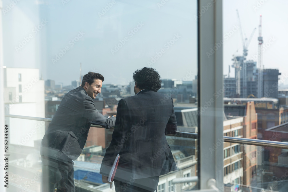 Businessmen talking on sunny, urban balcony Businessmen talking on sunny, urban balcony