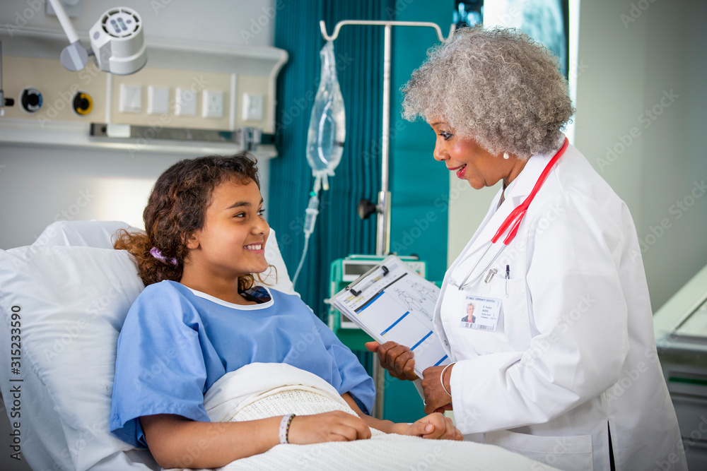 Female doctor talking with girl patient in hospital room Female doctor talking with girl patient in hospital room