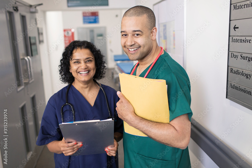 Portrait confident doctors with medical chart making rounds in hospital corridor Portrait confident doctors with medical chart making rounds in hospital corridor