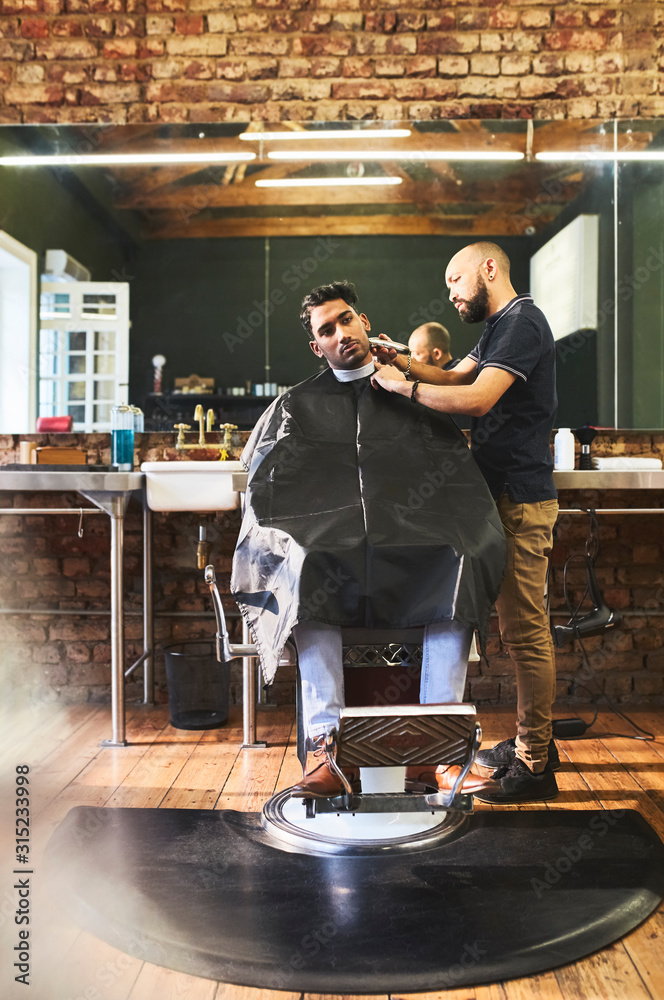 Male barber shaving face of customer in barbershop Male barber shaving face of customer in barbershop
