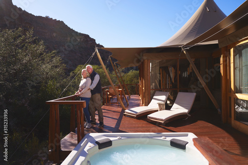 Affectionate senior couple on sunny luxury safari lodge balcony