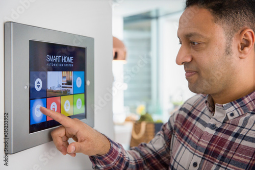 Man setting smart home navigation system alarm at touch screen photo