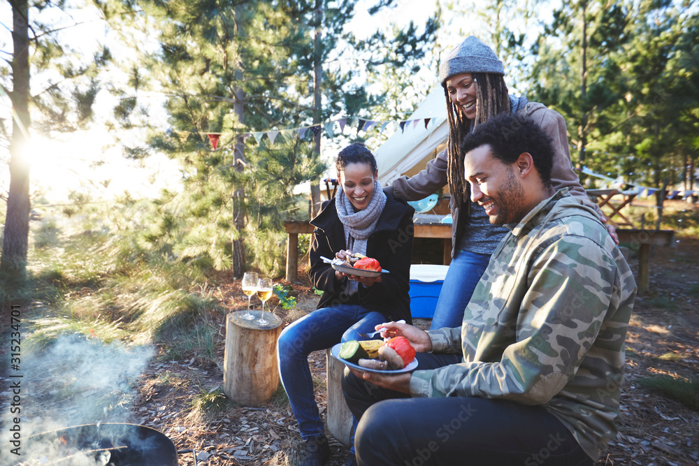 Happy friends eating at sunny campsite Happy friends eating at sunny campsite