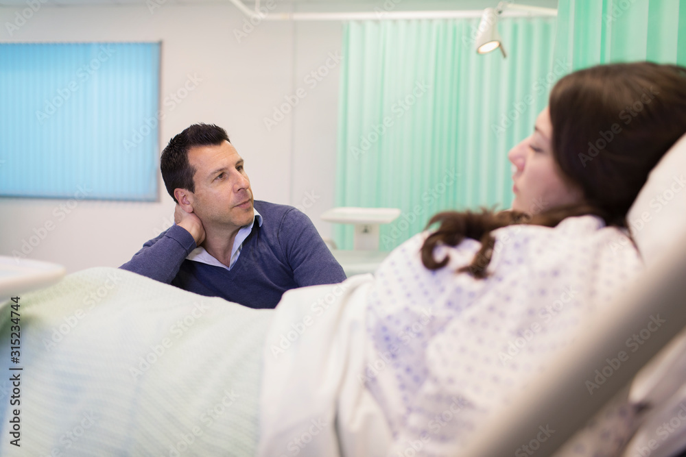 Man visiting wife resting in hospital bed