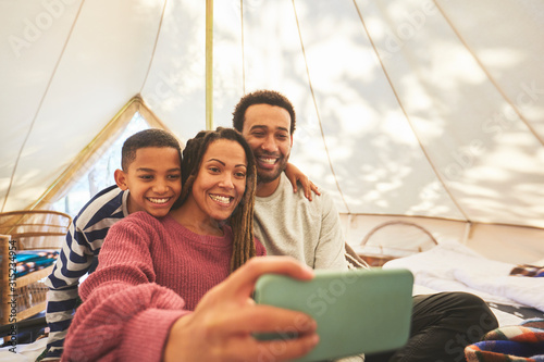 Happy, affectionate family taking selfie in camping yurt photo