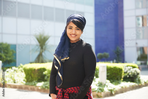 Portrait confident young woman wearing headscarf in sunny park