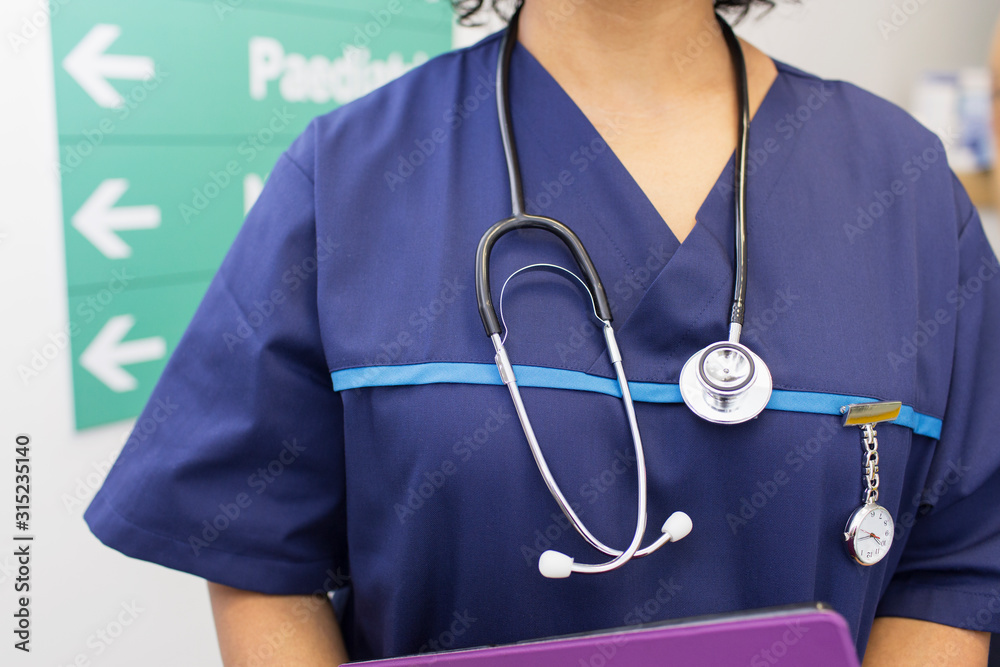 Close up female doctor wearing scrubs and stethoscope in hospital Close up female doctor wearing scrubs and stethoscope in hospital