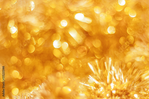 Abstract golden festive background. Defocused lights of golden tinsel with bokeh effect.