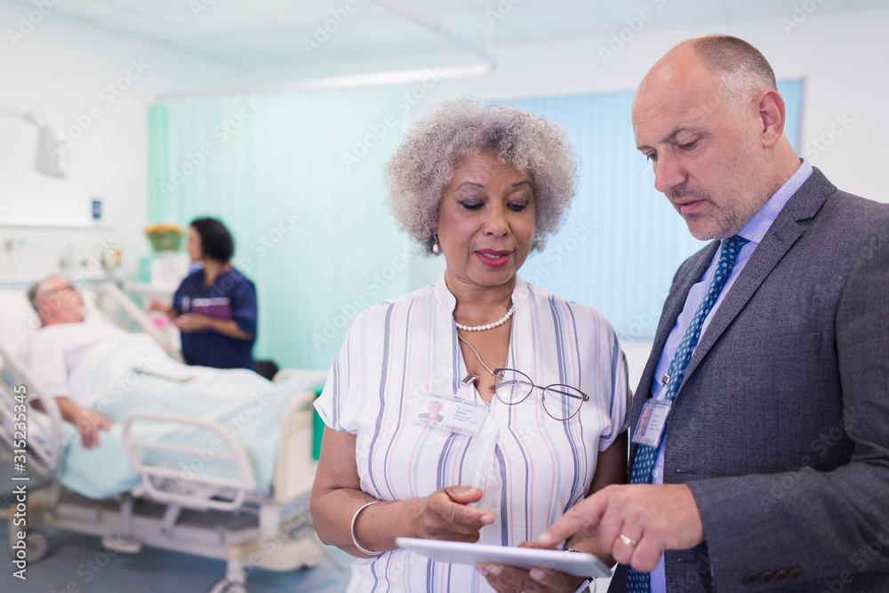 Doctors with digital tablet making rounds, consulting in hospital room Doctors with digital tablet making rounds, consulting in hospital room