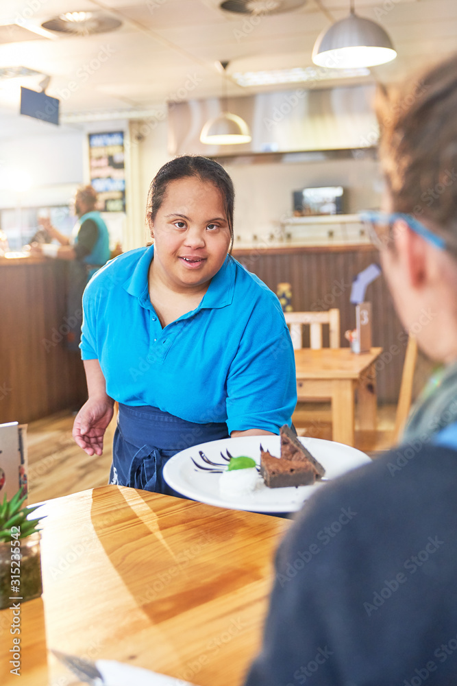 Young female server with Down Syndrome serving dessert in cafe Young female server with Down Syndrome serving dessert in cafe