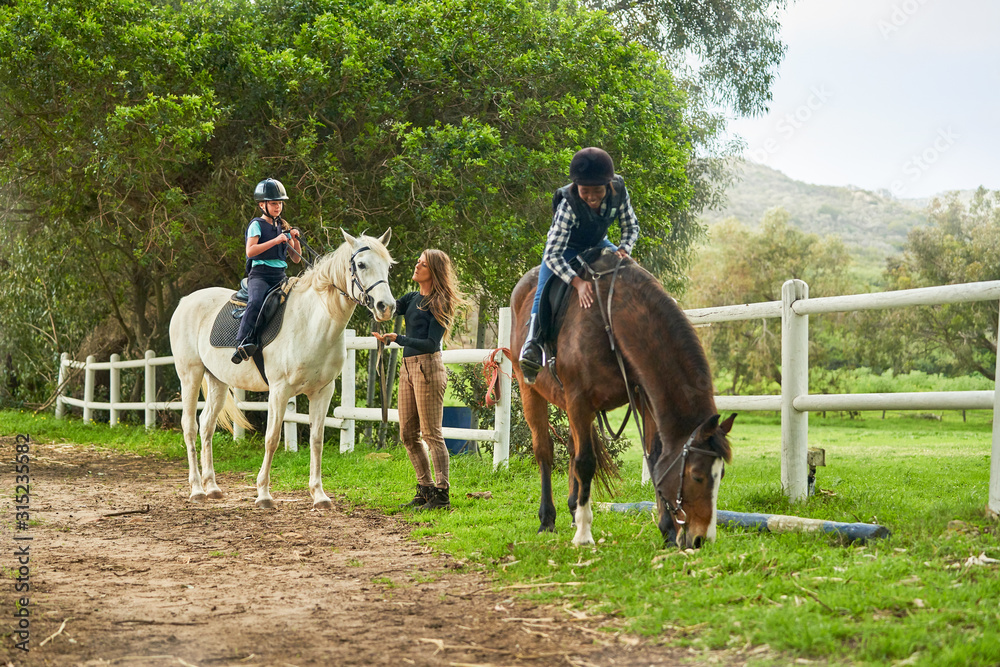 Girls preparing for horseback riding lesson at rural paddock Girls preparing for horseback riding lesson at rural paddock