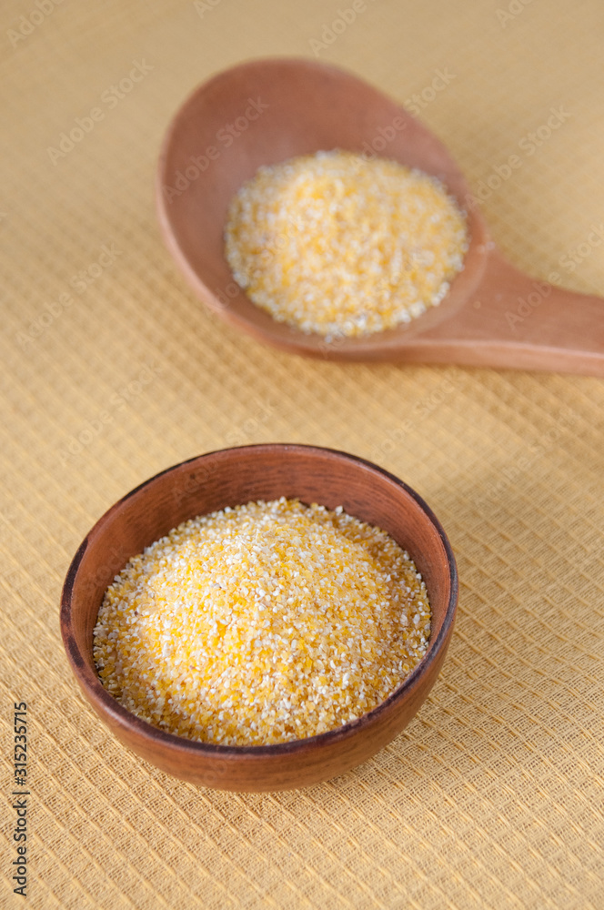 Clay Cup and wooden spoon with corn grits on the table, top view Clay Cup and wooden spoon with corn grits on the table, top view