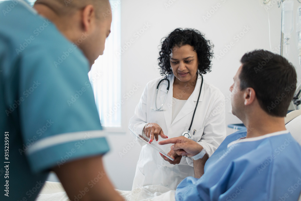 Doctor with digital tablet making rounds, talking with patient in hospital bed Doctor with digital tablet making rounds, talking with patient in hospital bed