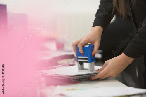 Businesswoman using stamp on paperwork in office photo