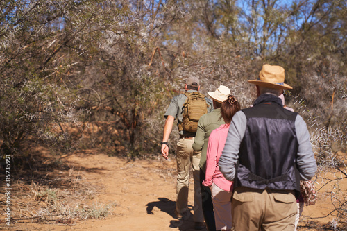 Safari tour guide leading group in sunny grassland South Africa