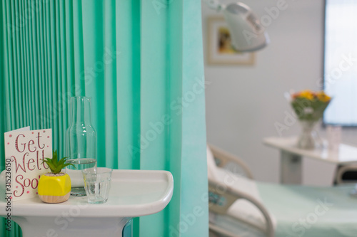 Get Well Soon card and water carafe on tray in vacant hospital room photo