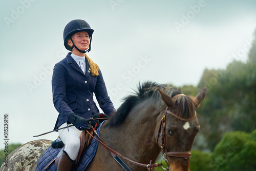 Confident smiling teenage girl equestrian horseback riding photo