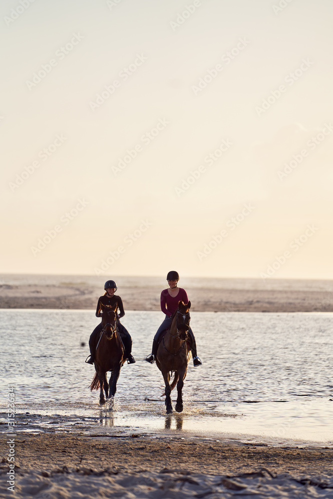 Young women horseback riding in ocean surf Young women horseback riding in ocean surf