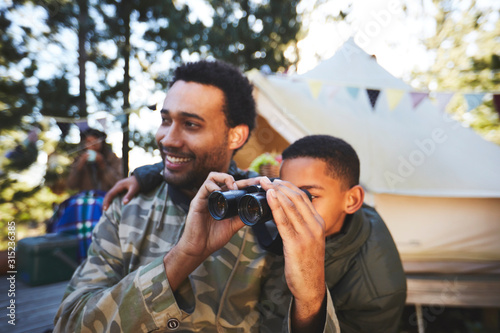 Curious father and son with binoculars at campsite photo