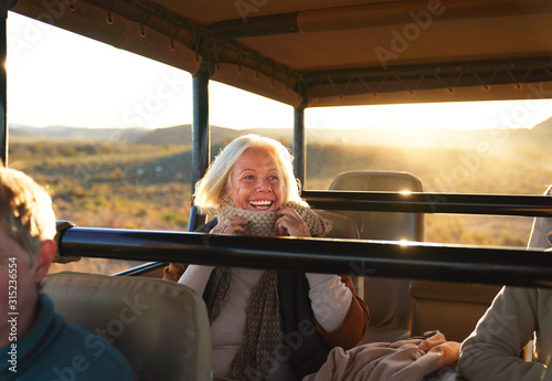 Happy senior woman on safari riding in off-road vehicle photo