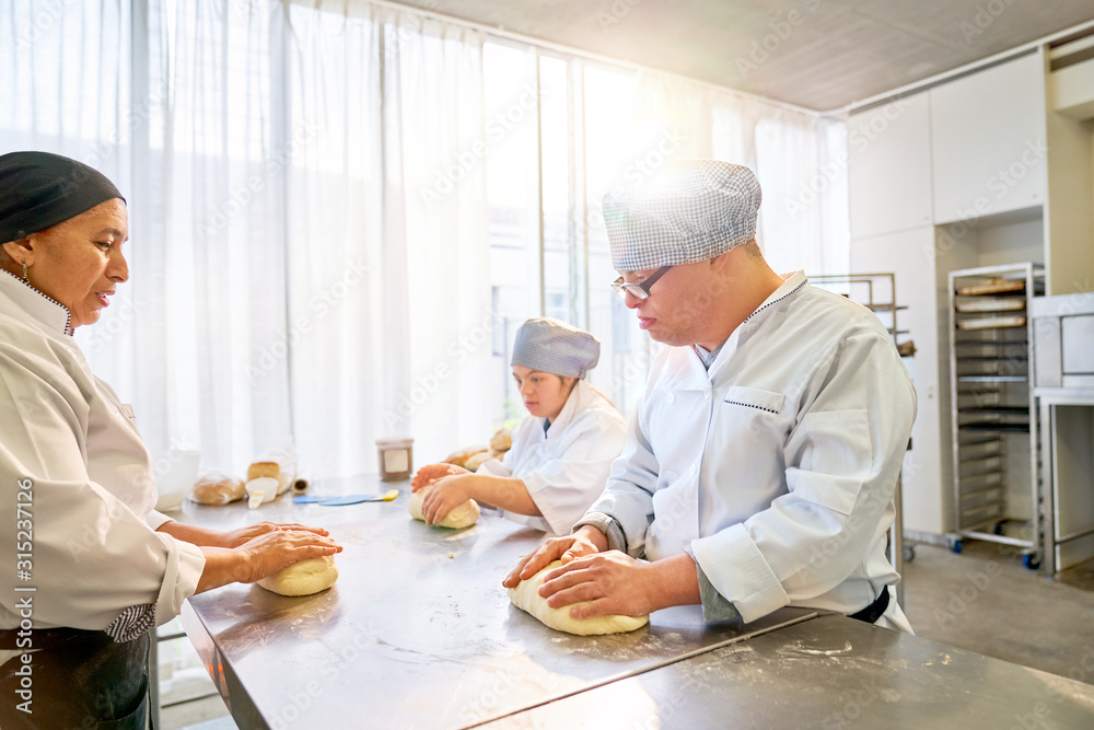 Chef teaching students with Down Syndrome how to bake in kitchen Chef teaching students with Down Syndrome how to bake in kitchen