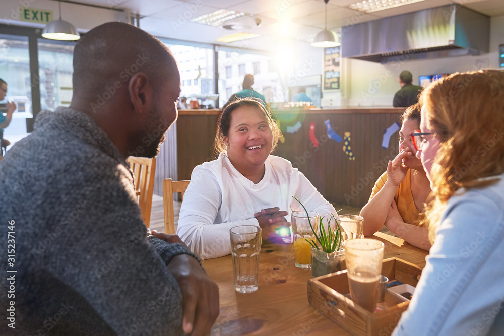 Happy young women with Down Syndrome in cafe with friends Happy young women with Down Syndrome in cafe with friends
