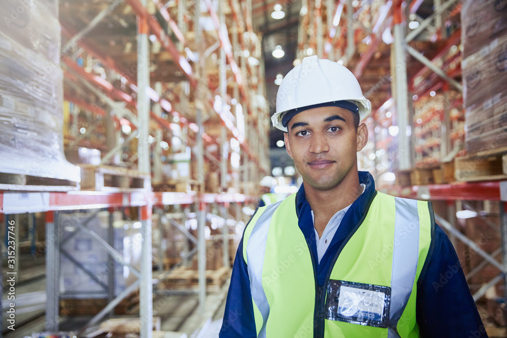 Portrait confident worker in hard-hat in distribution warehouse aisle Portrait confident worker in hard-hat in distribution warehouse aisle
