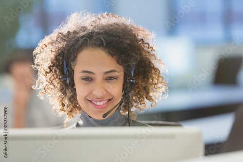 Businesswoman with headset working at computer in office