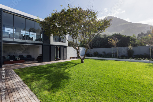 Sunny home showcase exterior lawn and tree below mountain photo