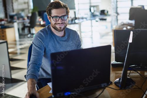 Portrait smiling businessman working at computer in office