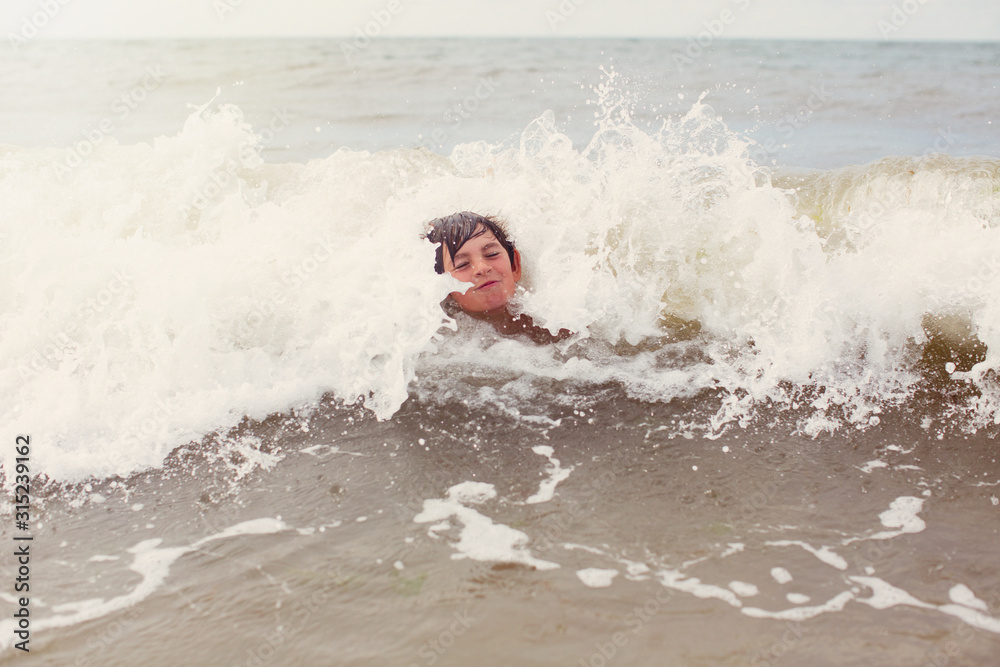 Waves splashing around boy swimming in summer ocean Waves splashing around boy swimming in summer ocean