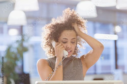 Businesswoman talking on telephone with hand in hair