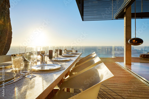 Sun shining over ocean behind luxury patio dining table with placesettings photo