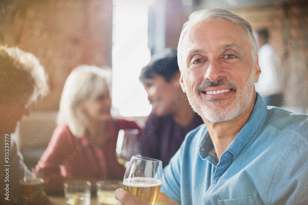 Portrait confident man drinking white wine with friends at restaurant table Portrait confident man drinking white wine with friends at restaurant table
