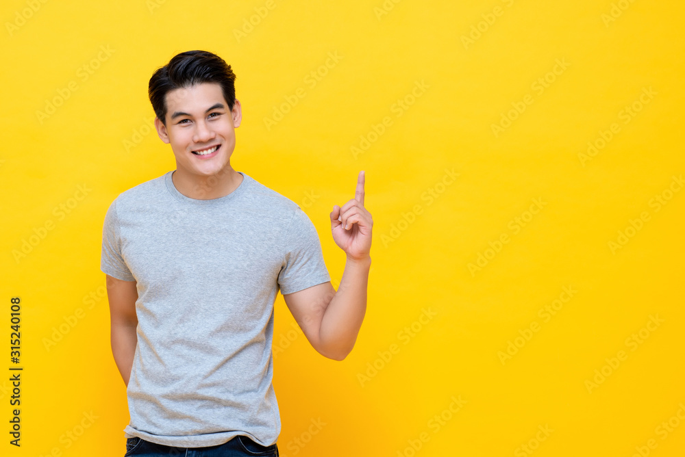 Happy smiling young handnsome Asian man pointing hand up - obrazy, fototapety, plakaty 