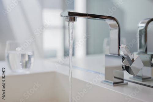 Water falling from modern bathroom faucet