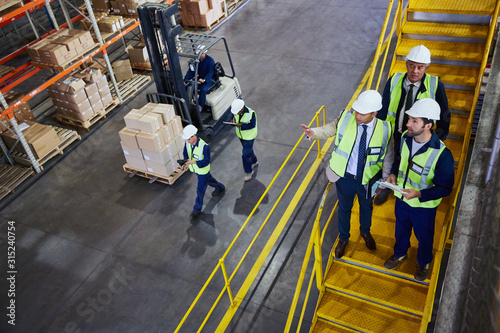 Forklift, managers and workers talking in distribution warehouse photo