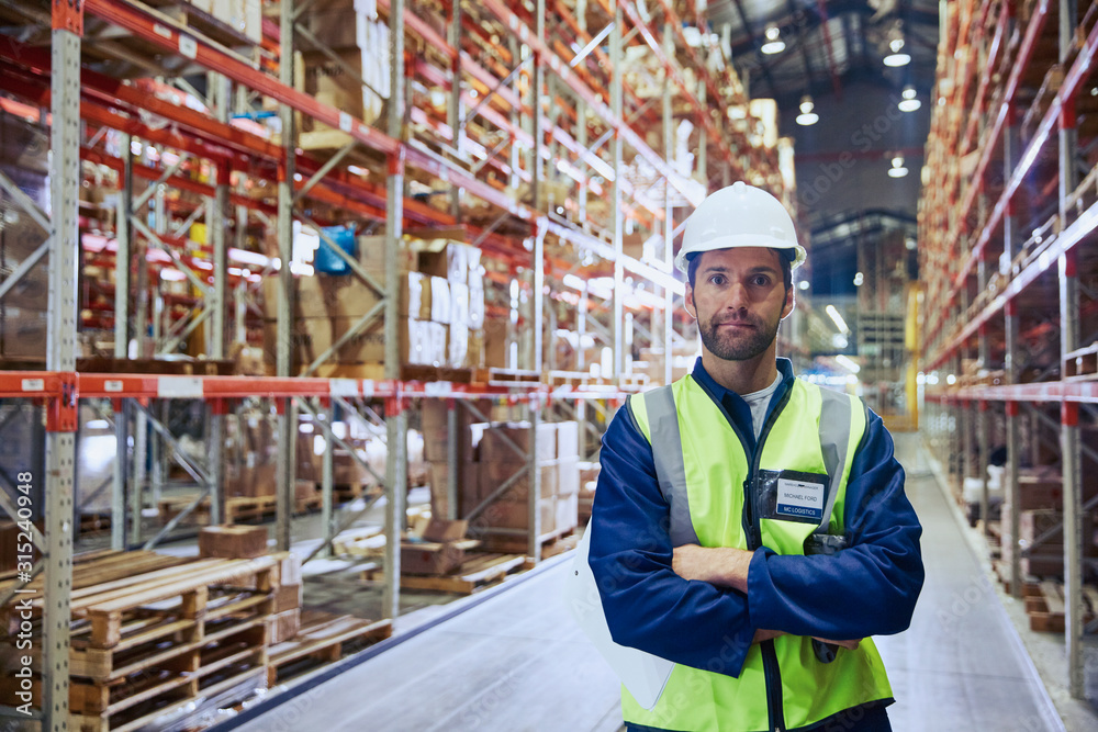 Portrait confident worker with arms crossed in distribution warehouse Portrait confident worker with arms crossed in distribution warehouse