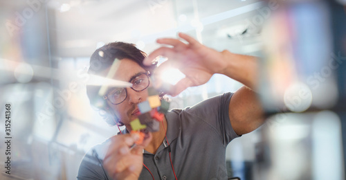 Focused, innovative male entrepreneur examining prototype photo