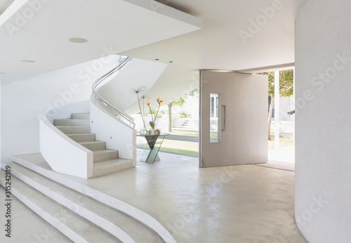 White foyer and spiral staircase in modern luxury home showcase interior photo