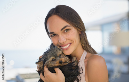 Portrait smiling woman cuddling small dog